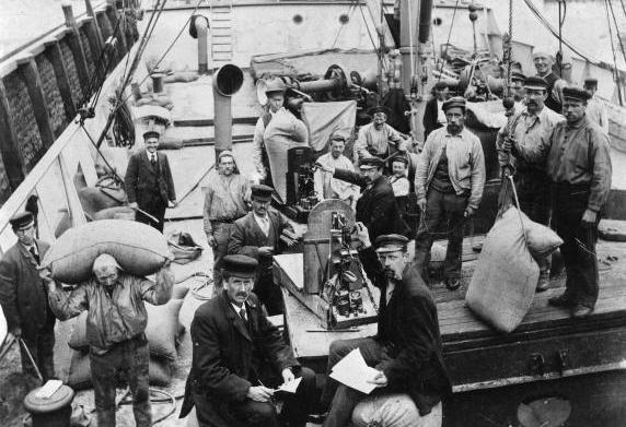 Havenarbeiders op een vrachtschip bezig met het lossen van zakken graan.