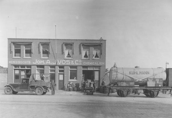 Oude foto van gevels met rechts een wagen voor vloeistof.