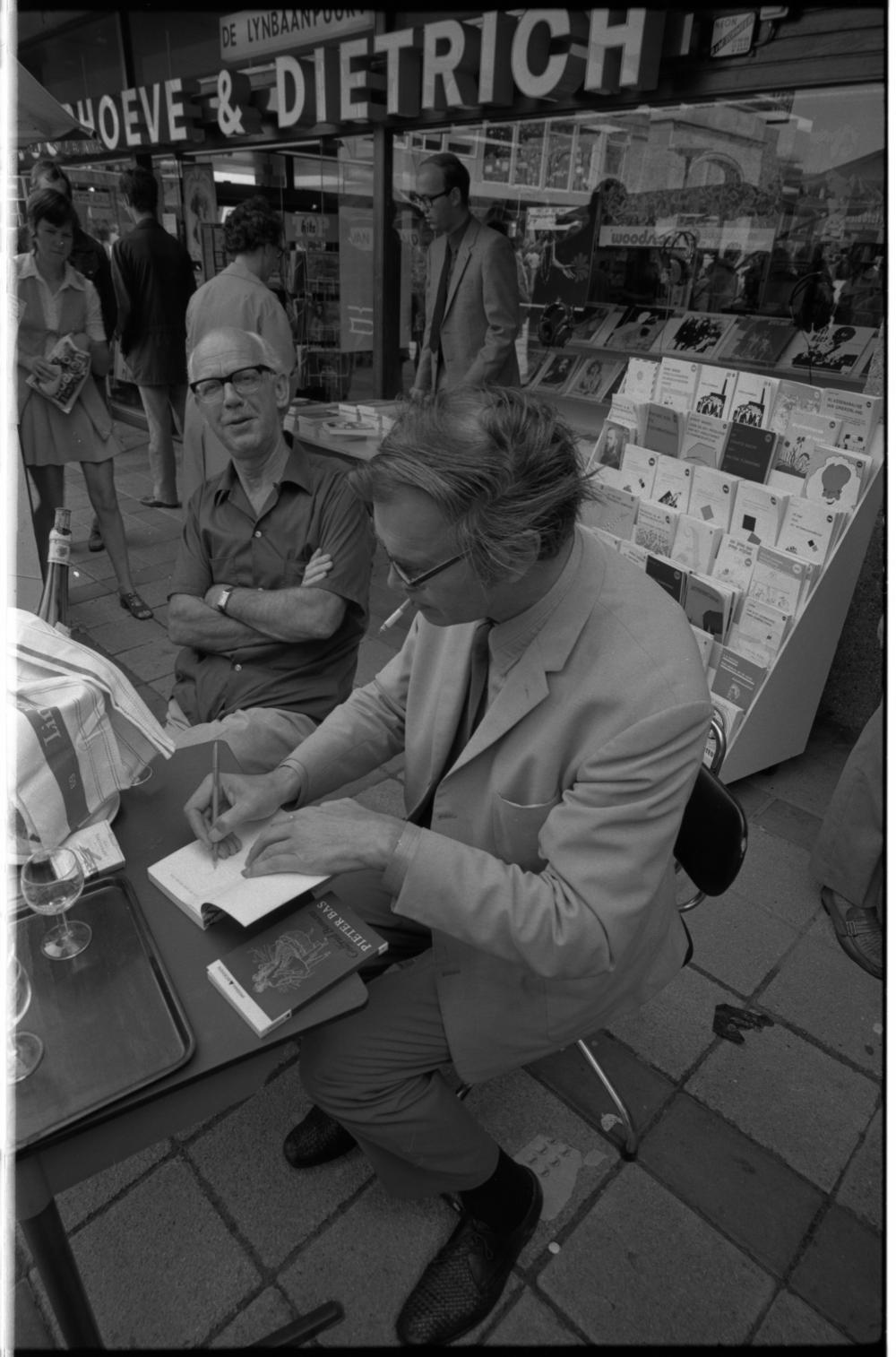 Foto van Godfried Bomans die iets signeert